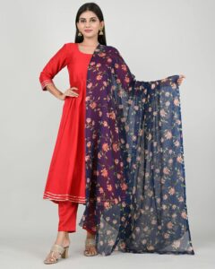 Portrait of a South Asian woman in a vibrant red salwar kameez with a floral dupatta on a white background.