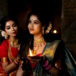 Two Indian women in sarees holding a diya, capturing the essence of elegance and tradition.